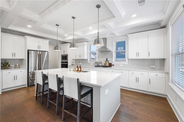 kitchen featuring dark wood-style floors, stainless steel appliances, visible vents, a sink, and wall chimney range hood