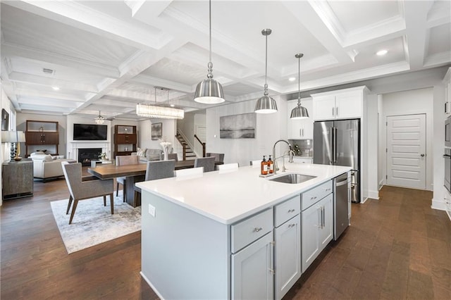 kitchen featuring a fireplace, stainless steel appliances, light countertops, dark wood-type flooring, and a sink