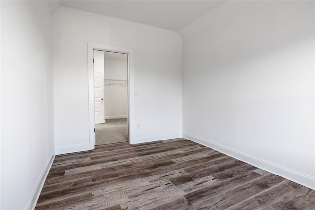 spare room with baseboards and dark wood-style flooring