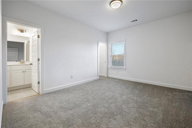 unfurnished bedroom featuring light carpet, baseboards, visible vents, connected bathroom, and a sink