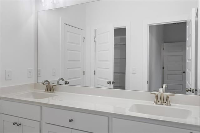 full bathroom with double vanity, a closet, and a sink