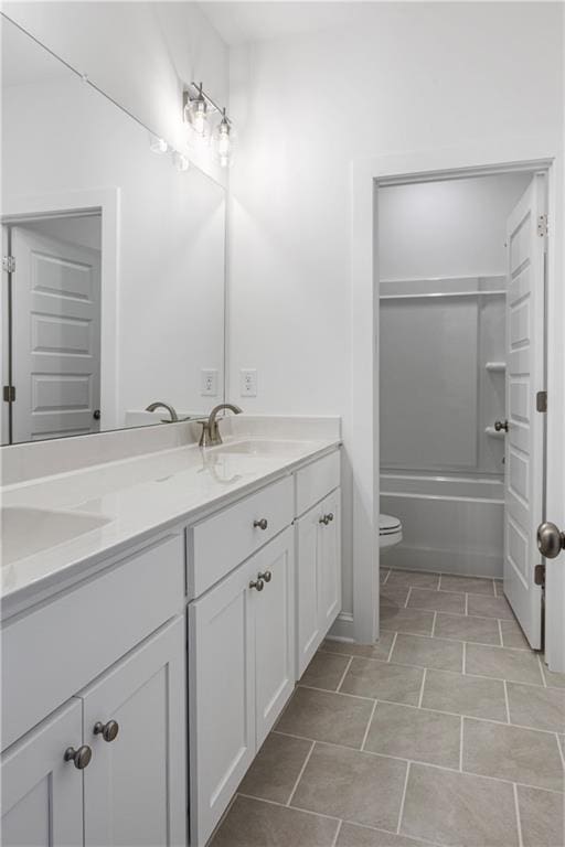 bathroom featuring tile patterned flooring, a sink, toilet, and double vanity