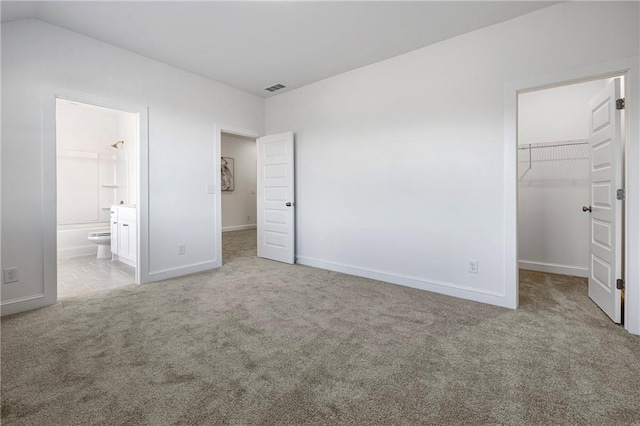 unfurnished bedroom featuring baseboards, visible vents, a spacious closet, carpet floors, and a closet