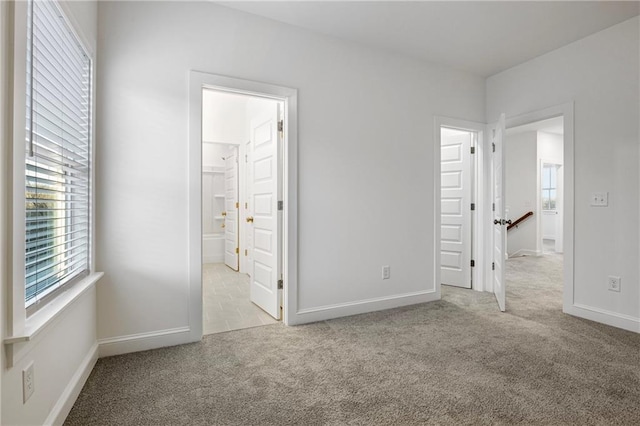 unfurnished bedroom featuring connected bathroom, baseboards, and carpet flooring