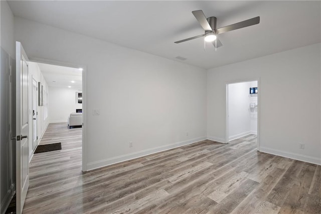 empty room featuring a ceiling fan, baseboards, and wood finished floors