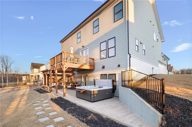 back of property featuring a deck, a patio area, fence, and a hot tub