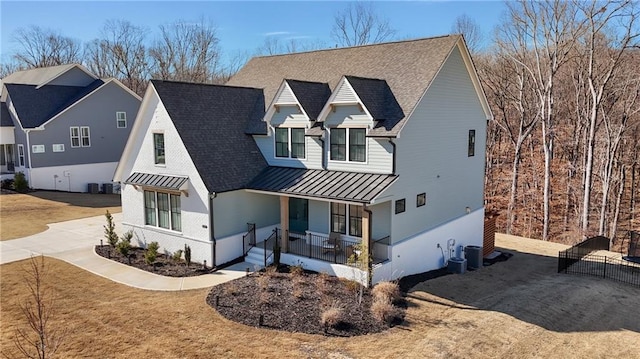 modern farmhouse style home featuring concrete driveway, metal roof, roof with shingles, covered porch, and a standing seam roof