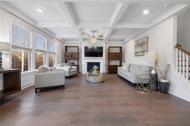 living room with ceiling fan, a fireplace, wood finished floors, stairway, and beamed ceiling