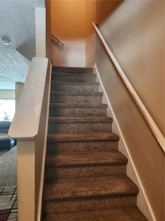 stairs featuring carpet floors and a textured ceiling