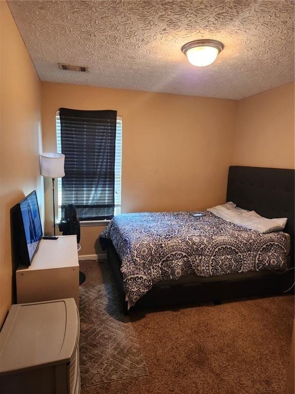 bedroom with dark colored carpet and a textured ceiling