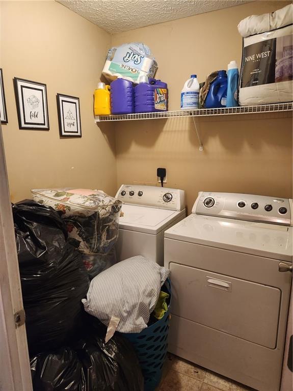 washroom featuring a textured ceiling, tile floors, and separate washer and dryer