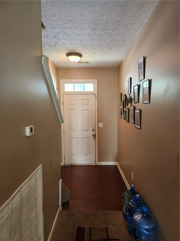 entryway featuring dark wood-type flooring and a textured ceiling