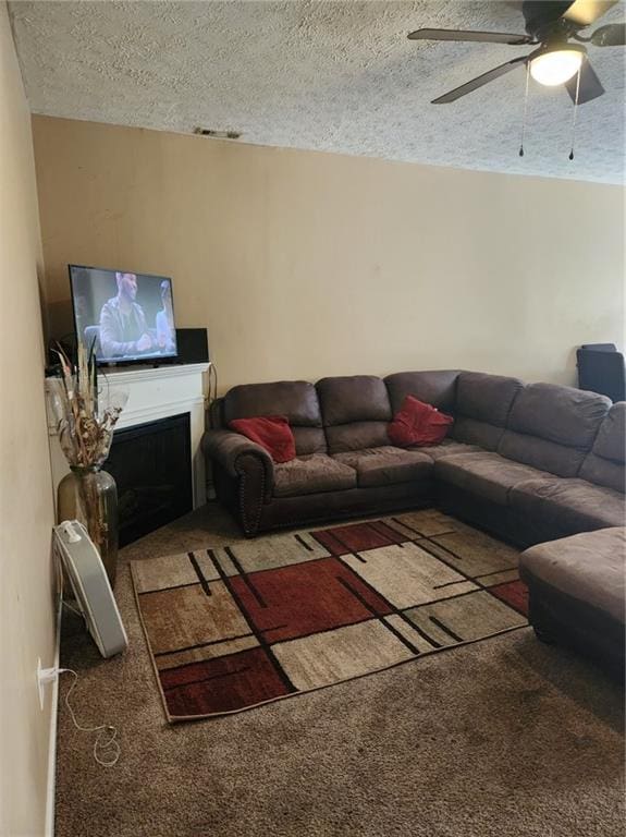 living room with a textured ceiling, ceiling fan, and dark colored carpet