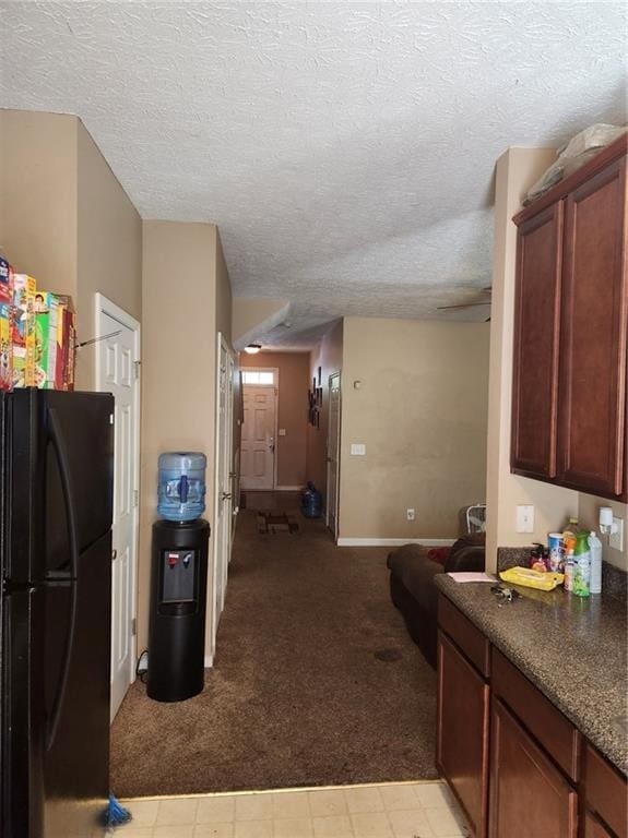 kitchen featuring light carpet, black refrigerator, and a textured ceiling