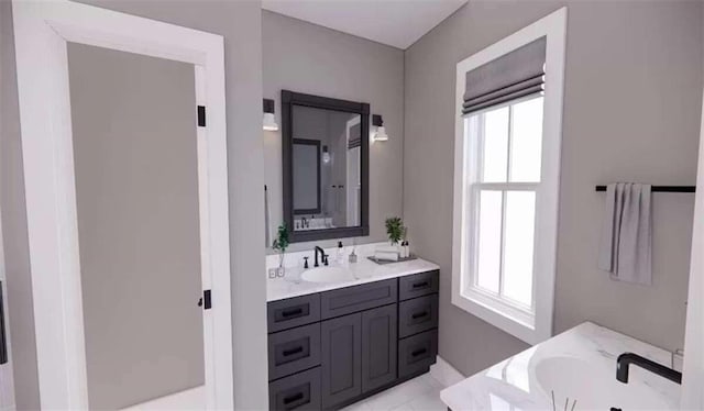 bathroom with vanity, a tub to relax in, and a healthy amount of sunlight