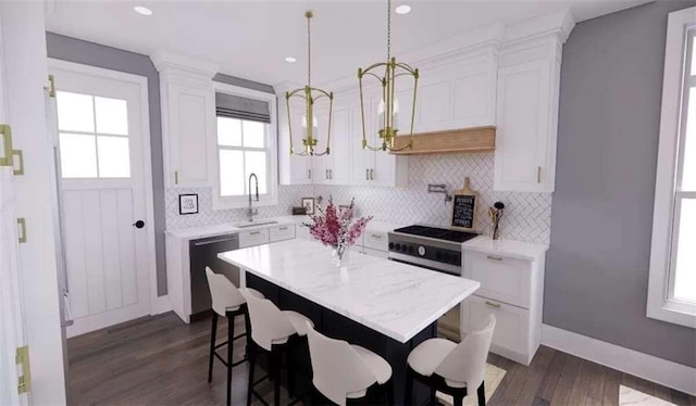 kitchen featuring appliances with stainless steel finishes, dark hardwood / wood-style flooring, a kitchen island, white cabinetry, and hanging light fixtures