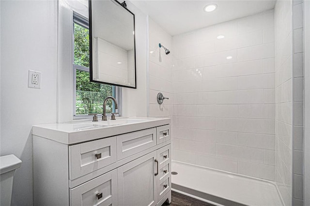 bathroom with tiled shower, vanity, toilet, and hardwood / wood-style floors