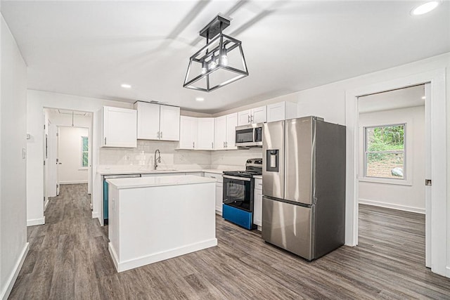 kitchen featuring sink, white cabinetry, hardwood / wood-style floors, stainless steel appliances, and a center island