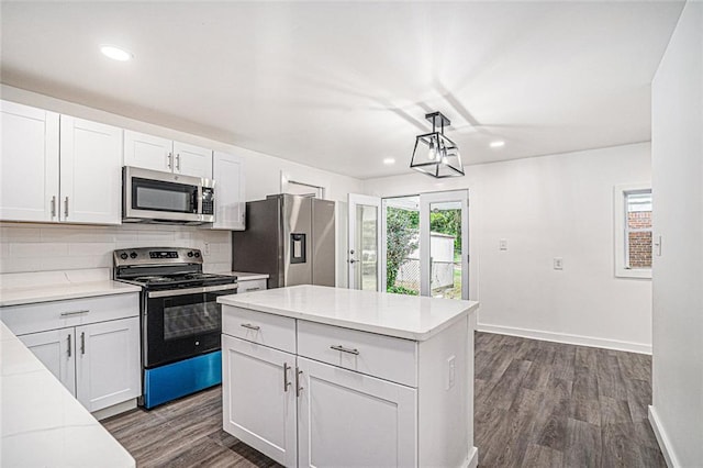 kitchen with white cabinetry, hanging light fixtures, stainless steel appliances, tasteful backsplash, and dark hardwood / wood-style flooring