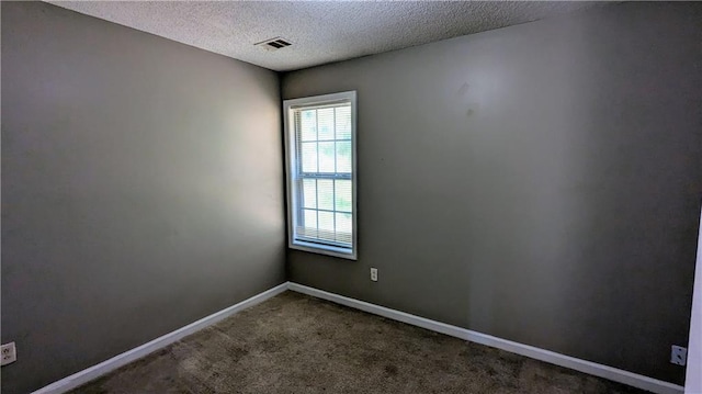 empty room with carpet floors and a textured ceiling