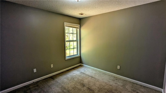 carpeted empty room with a textured ceiling