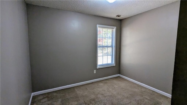 spare room with a textured ceiling and light colored carpet