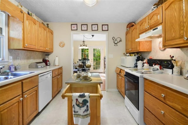 kitchen with decorative light fixtures, sink, backsplash, white appliances, and a textured ceiling