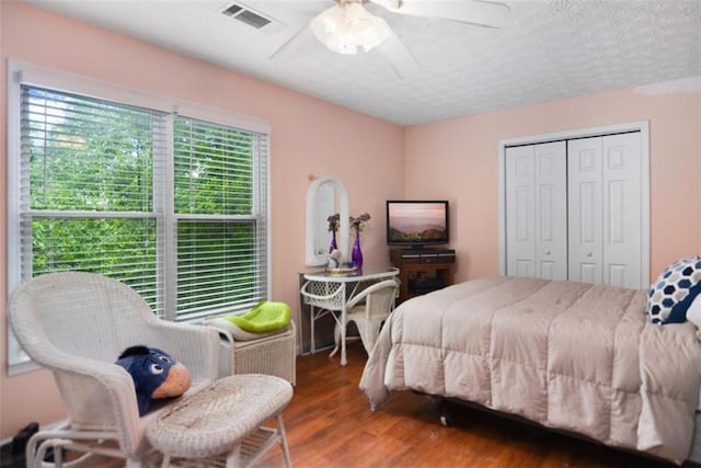 bedroom featuring a textured ceiling, wood-type flooring, a closet, and ceiling fan