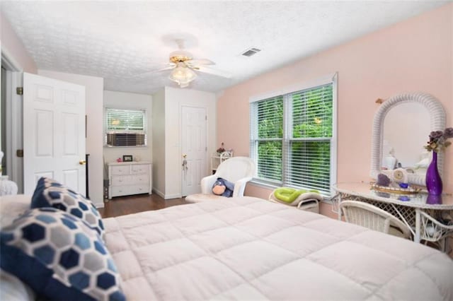 bedroom with multiple windows, ceiling fan, dark hardwood / wood-style floors, and a textured ceiling