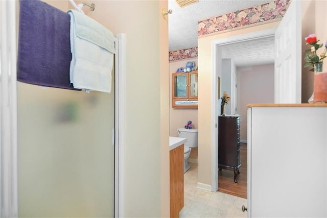 bathroom featuring vanity, an enclosed shower, a textured ceiling, and toilet