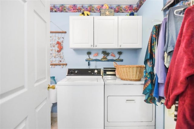 clothes washing area featuring cabinets and washer and dryer