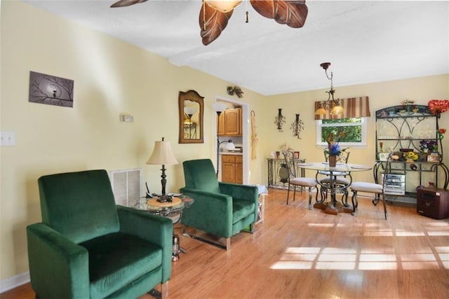 sitting room with beamed ceiling, ceiling fan, and light wood-type flooring