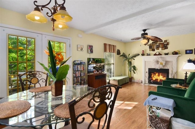 dining area with plenty of natural light, a textured ceiling, a high end fireplace, and light hardwood / wood-style floors