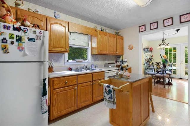 kitchen featuring french doors, sink, a textured ceiling, white refrigerator, and pendant lighting