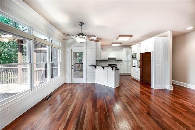 kitchen featuring dark wood-type flooring, stainless steel microwave, kitchen peninsula, and white cabinets