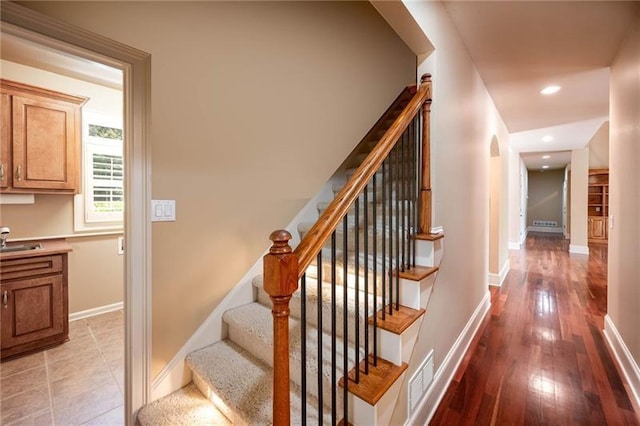 staircase featuring sink and hardwood / wood-style floors