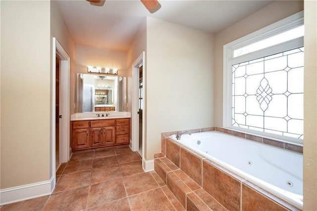 bathroom with ceiling fan, vanity, and tiled tub