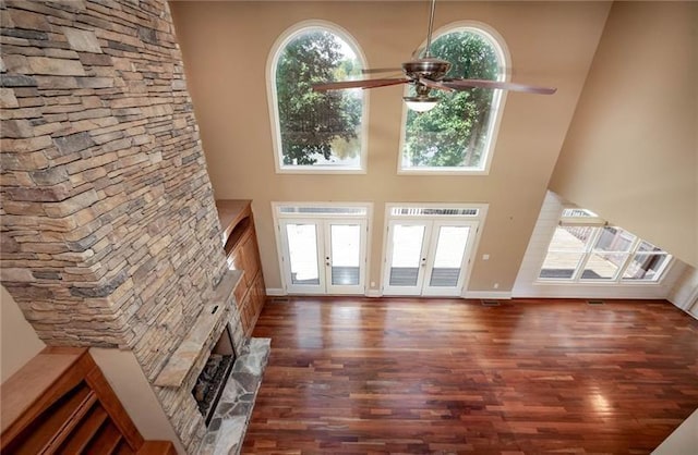 unfurnished living room with dark hardwood / wood-style floors, french doors, ceiling fan, and a high ceiling