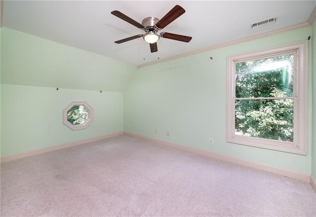 empty room featuring ceiling fan, ornamental molding, vaulted ceiling, and light carpet