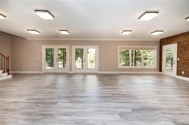 unfurnished room with french doors, ornamental molding, a healthy amount of sunlight, and light hardwood / wood-style floors