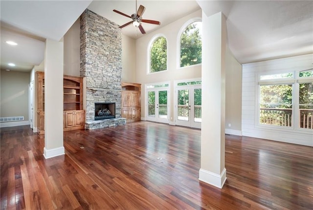 unfurnished living room with ceiling fan, a fireplace, dark hardwood / wood-style flooring, and a high ceiling