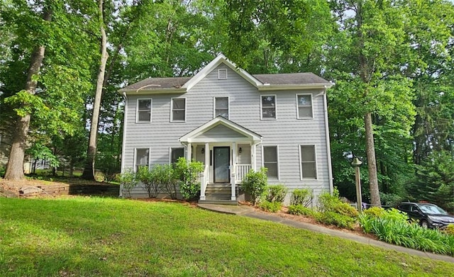 colonial home featuring a front lawn and view of wooded area