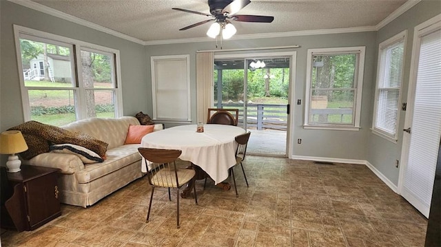 dining room featuring healthy amount of natural light, a ceiling fan, a textured ceiling, baseboards, and crown molding