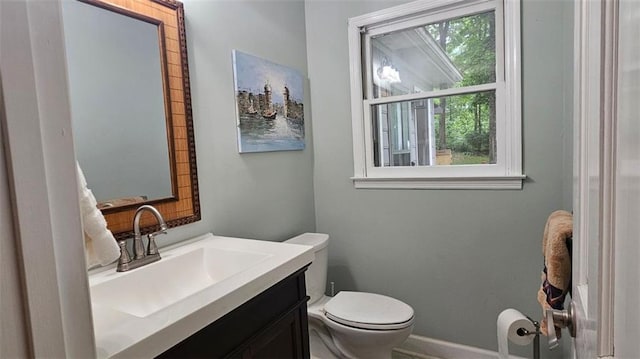 half bath with toilet, vanity, and baseboards