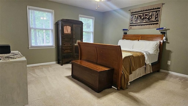 bedroom featuring light carpet, baseboards, and ceiling fan