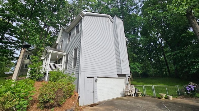 view of side of home featuring fence, driveway, an attached garage, and a chimney