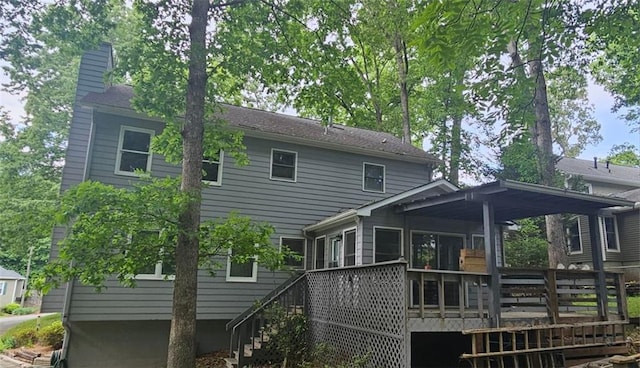 back of property featuring a deck, a chimney, stairway, and a sunroom