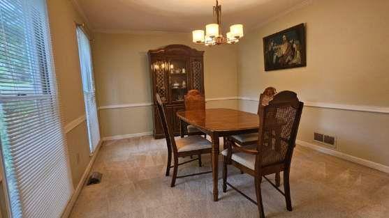 dining room featuring a chandelier, light carpet, baseboards, and ornamental molding