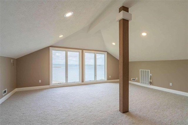 bonus room with visible vents, baseboards, light colored carpet, a textured ceiling, and lofted ceiling with beams