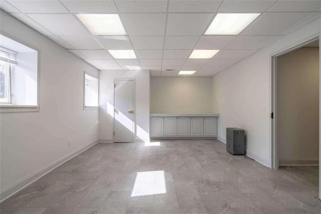 spare room featuring a healthy amount of sunlight, baseboards, and a paneled ceiling